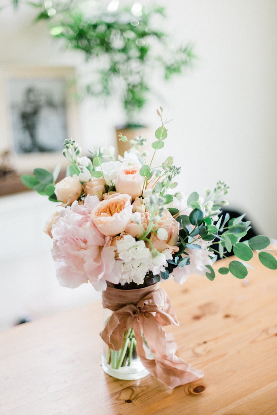 Peach and blush posy in a glass vase tied with a brown ribbon on a wooden table