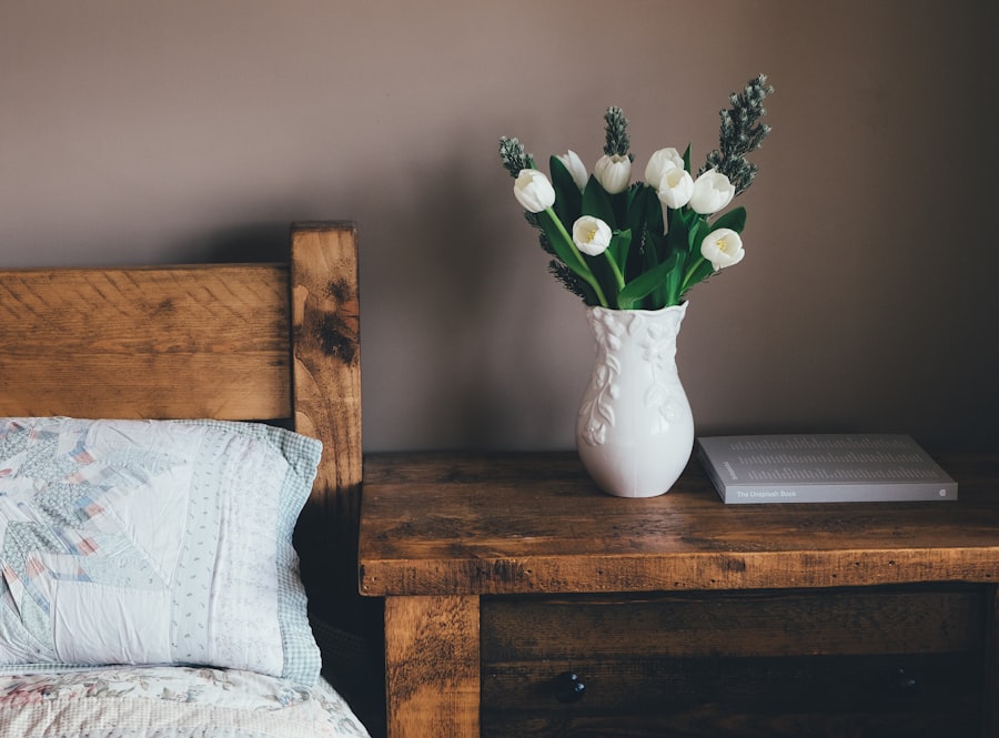 White tulips in a ceramic vase on a warm wooden side table